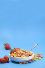 Corn rings with milk in a plate with berries and fruits on a white background. The concept of quick breakfast cereals