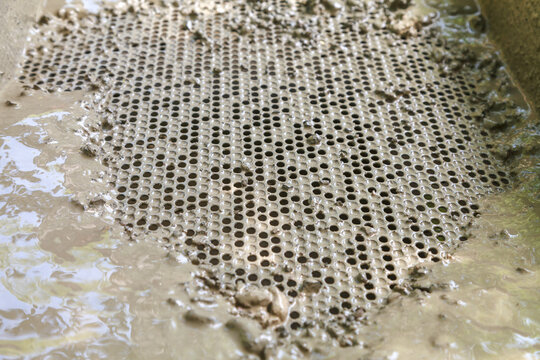 Metal sieve with round holes for cleaning dirty water from small stones