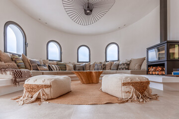 Round living space of Mediterranean villa with sofa in a semicircle along the wall, cushions,...