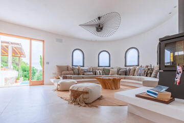 Mediterranean villa living room with portholes windows, sofa along the circumference, with numerous...