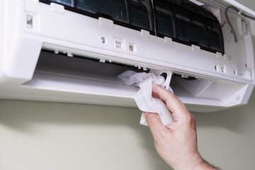 cleaning a dirty and dusty air conditioning filter in the house. male removing a dusty air conditioner filter.