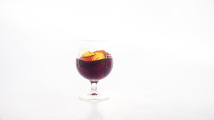 Red wine glass with ice making splash, on white background
