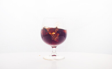 Red wine glass with ice making splash, on white background
