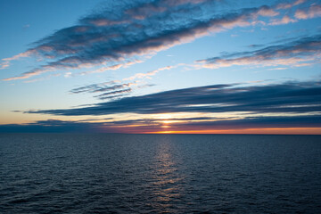 Bright orange sunset over the sea, streaks of sunlight across the sky.