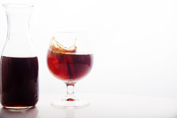 Red wine glass with ice making splash, on white background