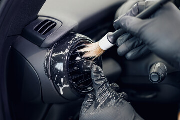 Cleaning the car interior with a brush. Auto detailing worker cleaning car interior, car detailing...