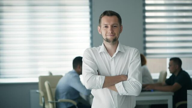 Portrait of happy office worker looking at camera in modern office, positive male employee with smiling face satisfied with good job career, close up portrait in slow motion