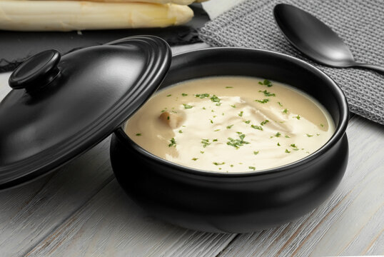 Delicious white asparagus cream soup on wooden background
