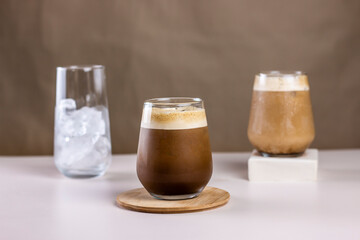 Cold coffee summer drink concept. Different size transparent glasses with ice cube and iced coffee...