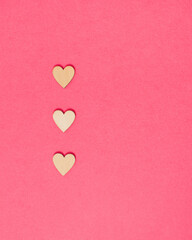 Three hearts laid out on vibrant pink colored background. Minimal love concept with copy space for message. Bright rose romance idea.