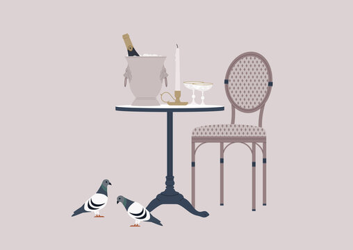 An outdoor french cafe table with a rattan chair, a champagne bucket, a candlestick, and sparkling wine glasses, pigeons walking nearby