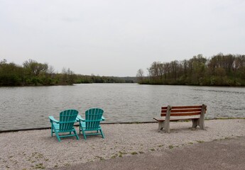 Fototapeta premium The bench and chairs at the lake on a cloudy day.