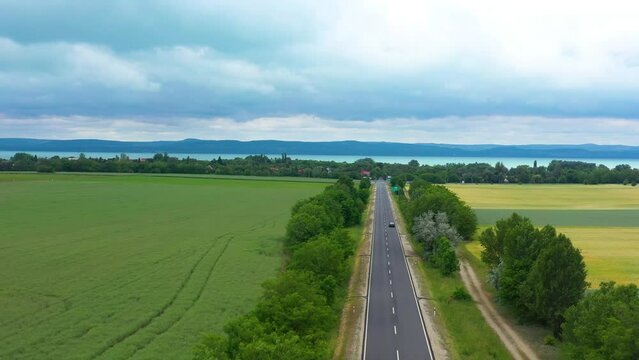 car goes to the lake on the highway with beautiful rainy background, drone footage