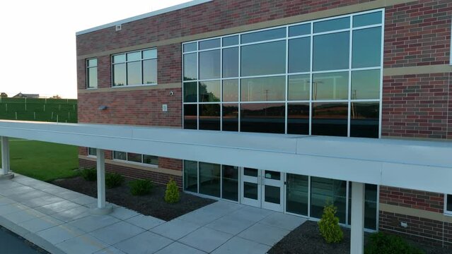 Aerial rising view of brand new elementary school in America. Reveals beautiful sunset causing flare on lens.