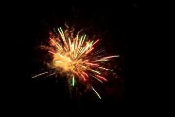 A portrait of fireworks exploding giving us a view on green, red and orange sprakles in the night...