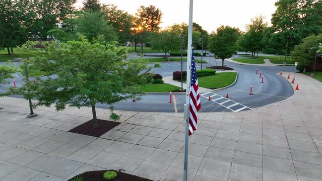 Stagnant flag at half staff. American school during spring sunset. Flag sits still at half mass after school shooting in America.