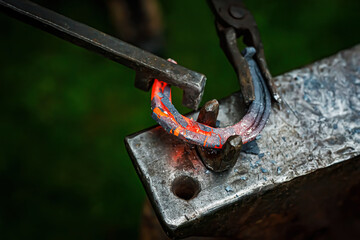 Horseshoe production process. A blacksmith bending hot metal on an anvil.