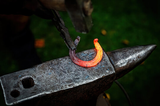 Horseshoe production process. A blacksmith bending hot metal on an anvil.