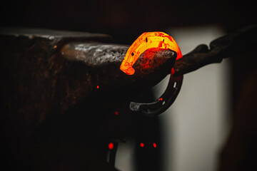 Horseshoe production process. A blacksmith bending hot metal on an anvil.