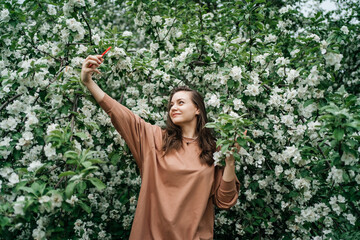 girl in blooming apple tree using smartphone video call outdoor nature