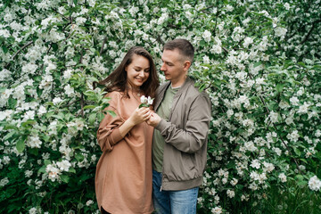 young couple in love girl and man hugging blooming apple tree aroma of flowers outdoors