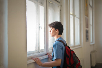young man in school looks out the window