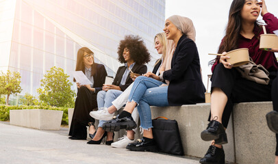 multiracial coworkers sitting lounging outside having lunch on steps