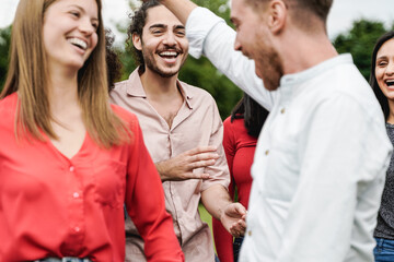 Multiethnic group of friends having fun dancing together outdoor during summer vacations - Focus on center man face