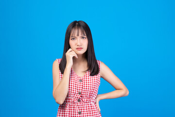 Young Asian beautiful woman wearing red dress on blue background suffering from headache desperate and stressed because pain and migraine. Hands to head.