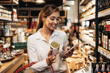 Beautiful young and elegant woman buying some healthy food and drink in modern supermarket or grocery store. Lifestyle and consumerism concept.