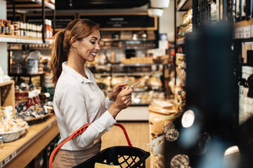 Beautiful young and elegant woman buying some healthy food and drink in modern supermarket or grocery store. Lifestyle and consumerism concept.
