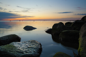 Fototapeta na wymiar Sea sunset landscape with rocks and beautiful orange sky with calm sea water surface