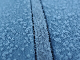 Abstract background. Frost needles close-up on the roof of a blue car.