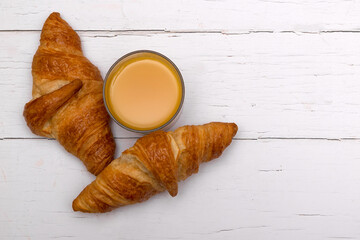 Fototapeta na wymiar Glass of orange juice and croissants on white wooden breakfast table. Flat lay with copy space 