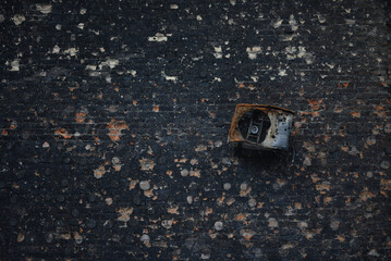 mangled air conditioning condenser unit hanging on outdoor wall of a burnt house as a result of the...