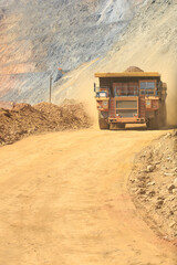 A quarry dump truck loaded with orange rock. Moving large dump trucks around the quarry.  Open-pit mining technology. © MaksimM