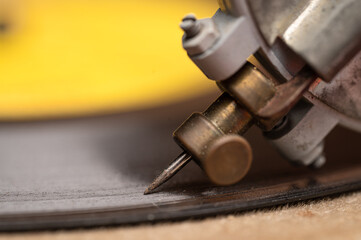 Close up of old time vintage antique record player needle in record groove, child's toy record player speaker
