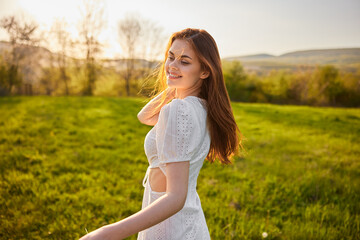 Fototapeta na wymiar happy woman in a light dress walks through the field during sunset