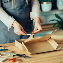 Close Up Photo Of Woman Hands Packing Christmas Ornaments Of Clay For Shipping At Her Store