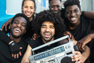 Happy group of multiracial people having fun listening music with vintage boombox outdoor - Youth...