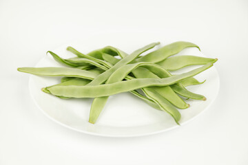 Green string beans on a white plate, vegetarian food.