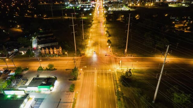 Top view time-lapse of car traffic at intersection lane and buildings. Long exposure timelapse of urban cityscape at night. Modern city in Canada full of night lights from energy and power.