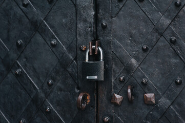 Padlock on an old forged black metal door with stripes and rivets. Fragment of the Boim Chapel in...