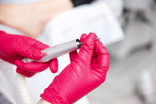 Peeling feet with special electric device. Professional hardware pedicure electric machine in hand of podologist