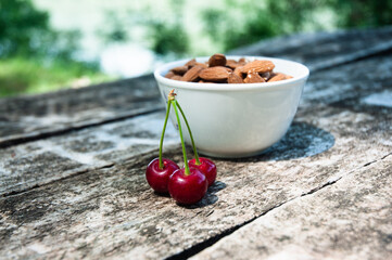 Cherries and almonds on a wooden table in nature.