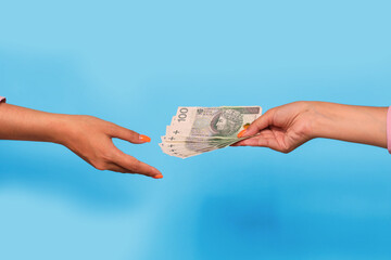 Hand giving polish zloty currency and hand take, over blue background. Giving money to help