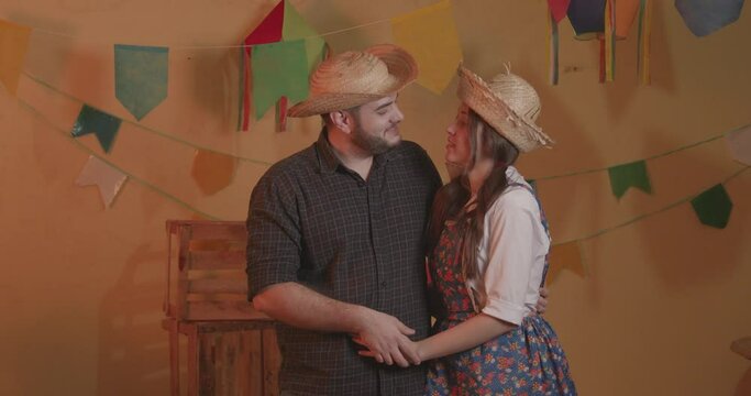 Beautiful couple wearing typical clothes for the Festa Junina. Smiling, happy. Kiss