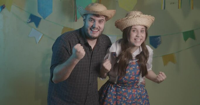 Beautiful couple wearing typical clothes for the Festa Junina. Cheering, celebrating, victory.