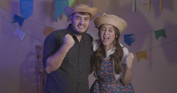 Beautiful couple wearing typical clothes for the Festa Junina. Cheering, celebrating, victory.
