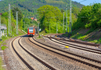 A typical regional commuter train enters a suburban station in Germany via a track system with several tracks